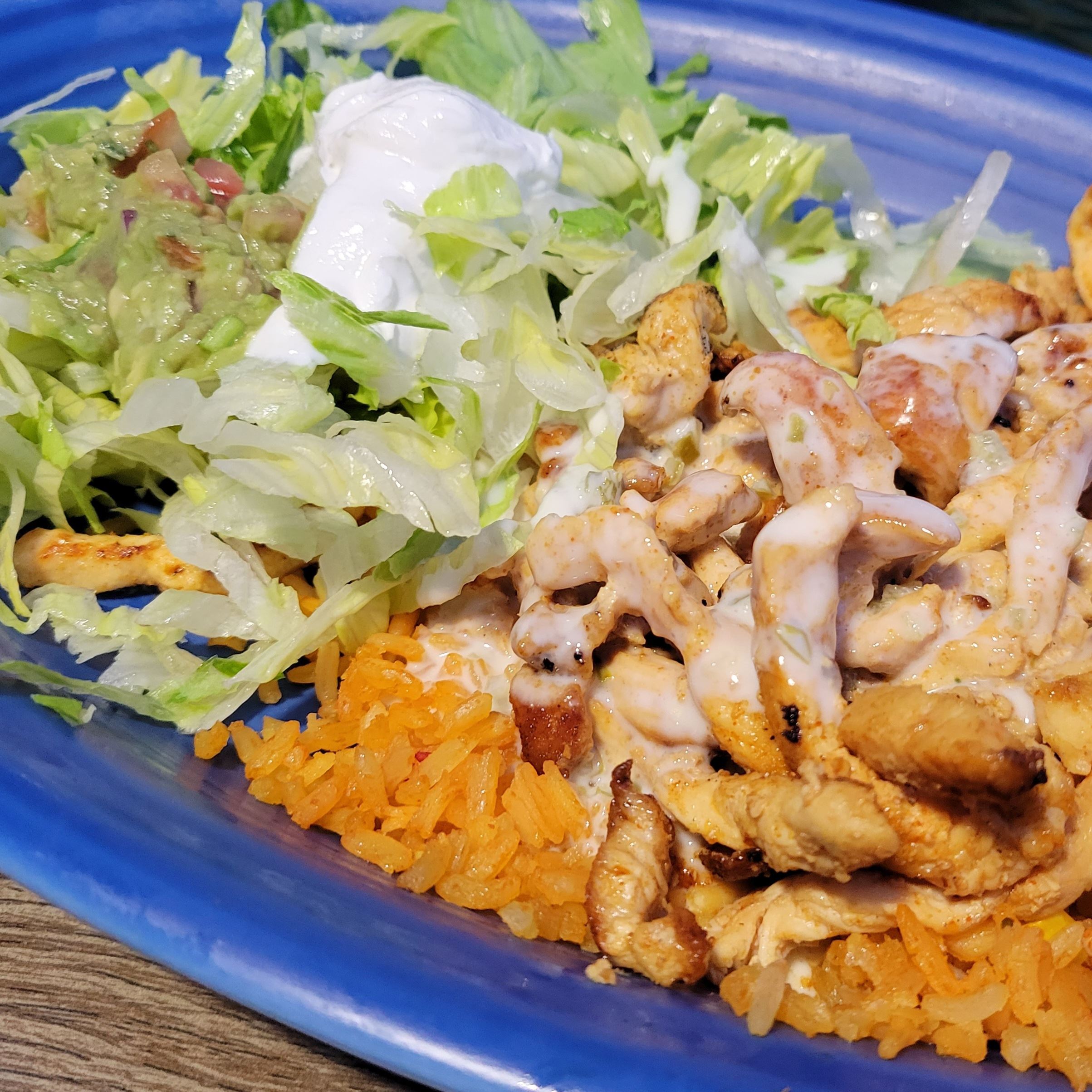 Chicken and rice covered in queso with lettuce and guacomole