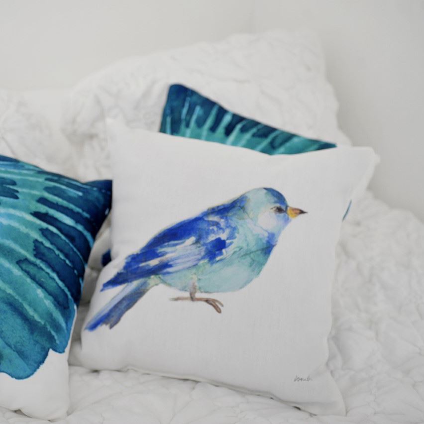 White pillow with a blue bird on a bed
