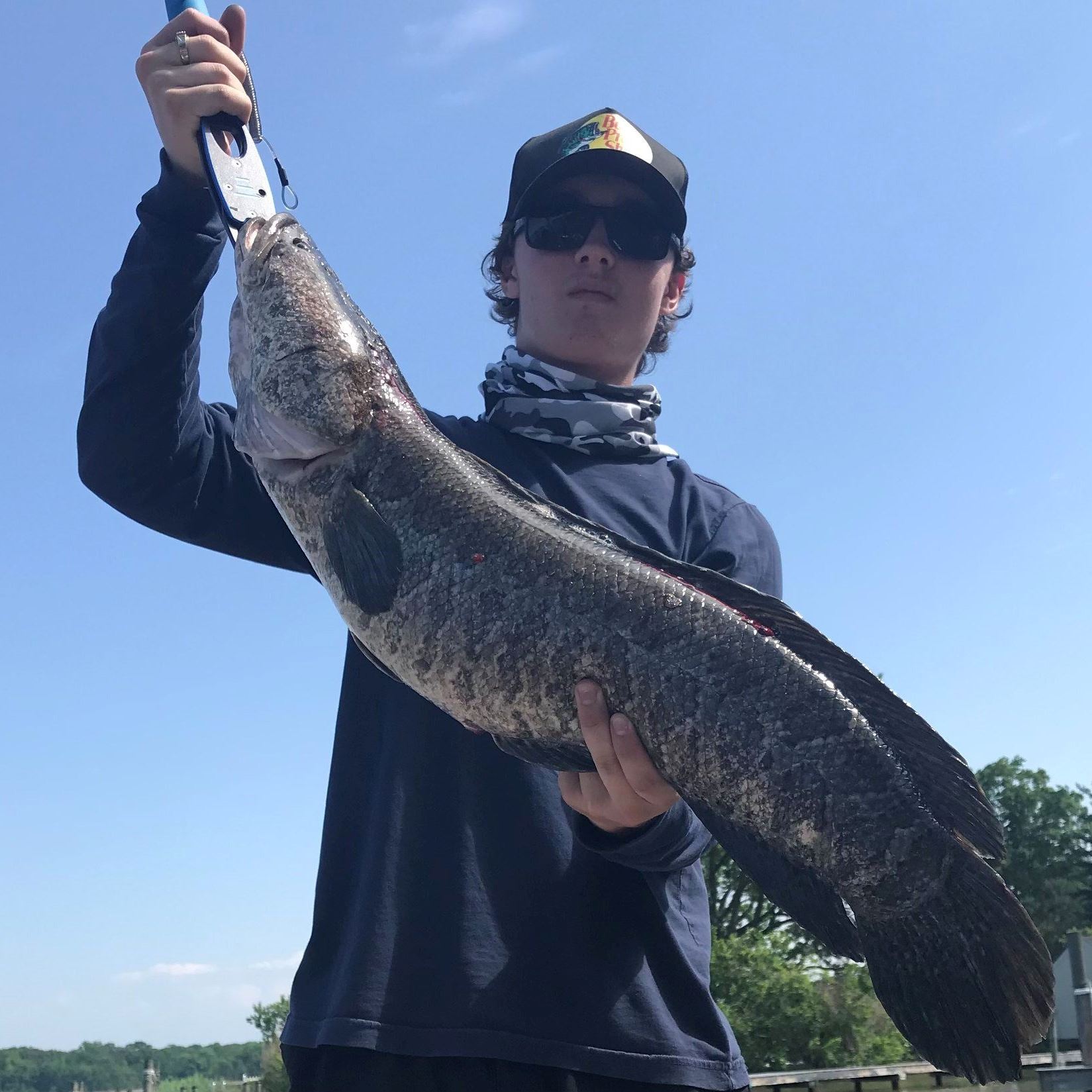 Man with hat and sunglasses holding Snakehead Fish